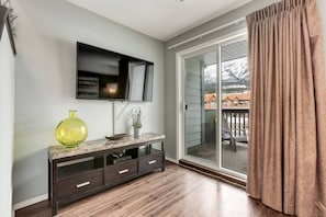 Relax in this stylish living room with a flat-screen TV, console table, and sliding glass door to an outdoor area.