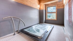 Een sauna met een glazen vloer, houten plafond en een raam met uitzicht op bomen.