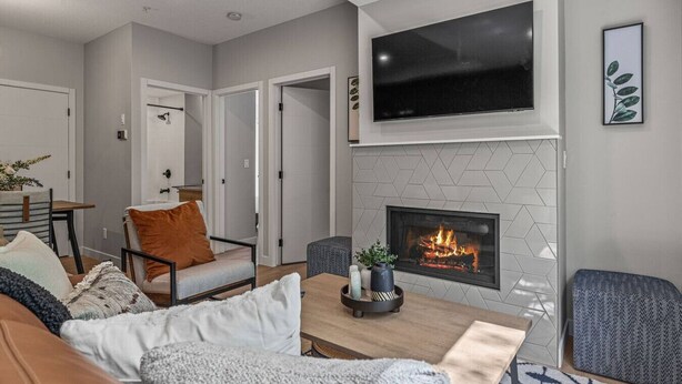Una sala de estar moderna con chimenea, zona de estar y televisor montado arriba.