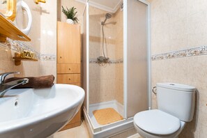 A bathroom with a sink, toilet, shower, and wooden cabinet. - MalagaSuite El Levante Apartment 1 (Torremolinos)