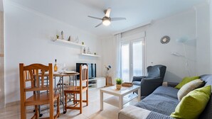 Una sala de estar moderna con comedor, ventilador de techo, televisor y ventana con persianas.