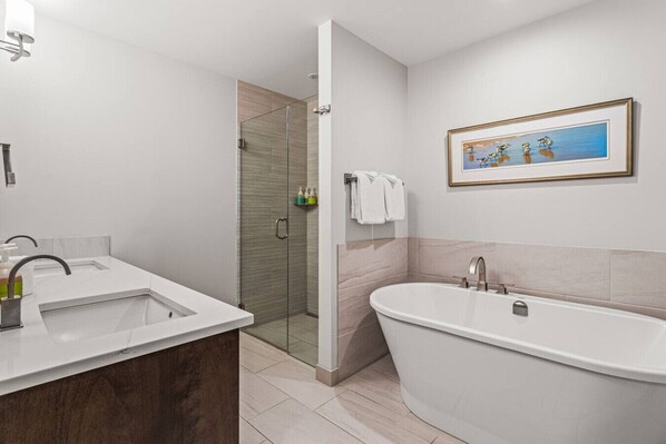 Un baño moderno con una bañera independiente, cabina de ducha con mampara de vidrio y un espejo grande.