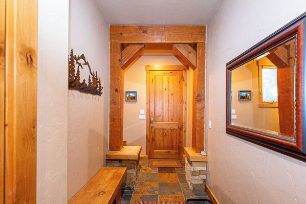 A wooden hallway with a door, benches, and a mirror.