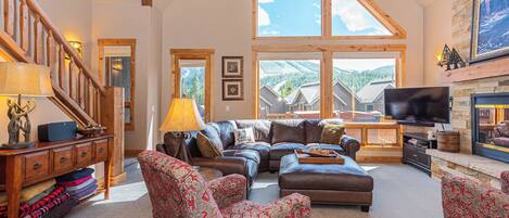 A spacious living room with a large window, a fireplace, and a television.