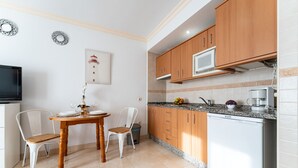 A compact kitchen with wooden cabinets, a built-in microwave, and a granite countertop.