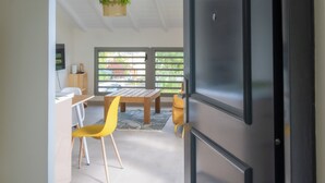 Una cocina moderna con un refrigerador negro, una mesa de comedor de madera, sillas amarillas y una planta colgante.