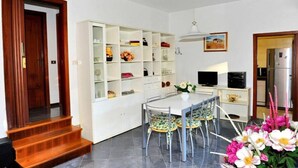 Une cuisine moderne avec des meubles blancs, une table à manger avec des chaises et une bibliothèque intégrée.