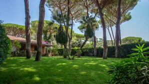 Un jardin luxuriant, avec de grands arbres et un bâtiment doté d’un toit en tuiles.