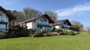 A modern two-story house with large windows, a covered outdoor seating area, and a well-maintained lawn. - Fishers View - a lodge that sleeps 10 guests in 5 bedrooms (St Ives)