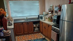 Una cocina compacta con armarios de madera, un lavamanos, una estufa y un refrigerador.