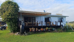 Una casa móvil con porche cubierto, antena parabólica y plantas en macetas.