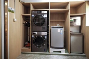 A compact laundry room with stacked washers and dryers, a microwave, and a small refrigerator. - Homeinn Pebble Hotel (Beijing West Railway Station South Square) (Beijing)