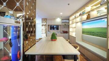 Un comedor moderno con una mesa larga, sillas, un acuario y un ventanal con vistas al paisaje.