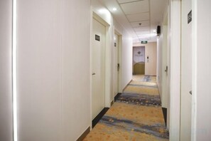 A hotel corridor with doors on both sides, carpeted with a floral pattern, and a ceiling with recessed lighting. - Homeinn Pebble Hotel (Beijing West Railway Station South Square) (Beijing)