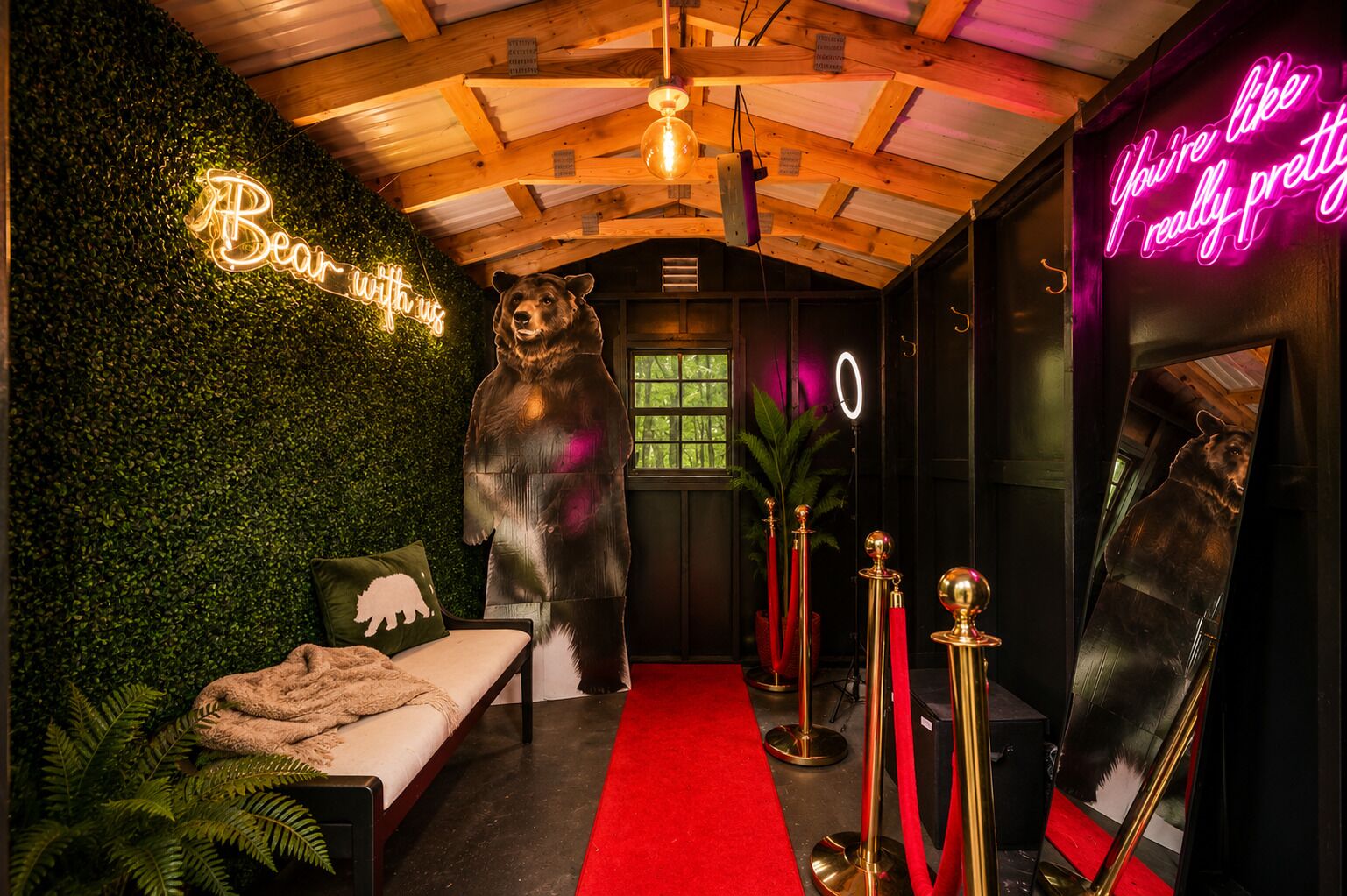 Una habitación con una estatua de oso, un letrero de neón, una alfombra roja y un espejo.