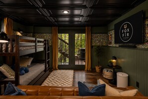A cozy room with a bunk bed, a leather sofa, a television, and a window with curtains. - Escape to our luxe, pet-friendly Blue Ridge cabin—sleeps 14 with top amenities! (Blue Ridge)