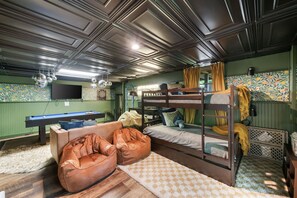 A room with bunk beds, a pool table, bean bags, and a dartboard.