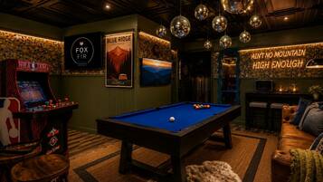Een pooltafel in een ruimte met spelautomaten, een poster van Blue Ridge, Georgia, en een bord waarop staat 'Ain't no mountain high enough'.