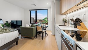 Un appartement moderne comprenant un canapé, une table à manger, un téléviseur et une cuisine équipée d’une cuisinière et de couteaux.