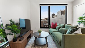 Un salon moderne avec un téléviseur à écran plat, un canapé vert et une table basse.