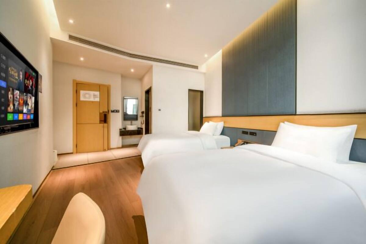 Una habitación de hotel con una cama grande, un escritorio, un televisor y un baño visible a través de una puerta abierta.