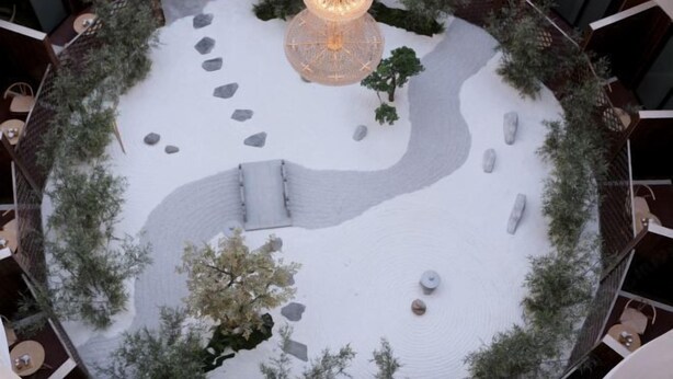 Un patio circular con una lámpara decorativa en el centro, rodeado de árboles y rocas.