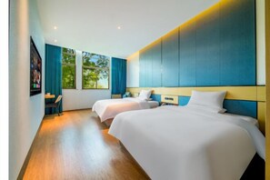 Habitación de hotel con dos camas, televisión y ventanas amplias con cortinas.