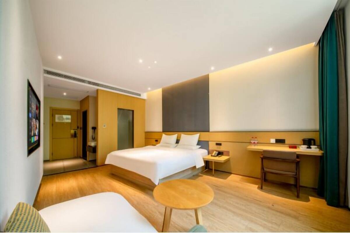 Una habitación de hotel con cama, escritorio, silla, una mesita redonda y espejo.
