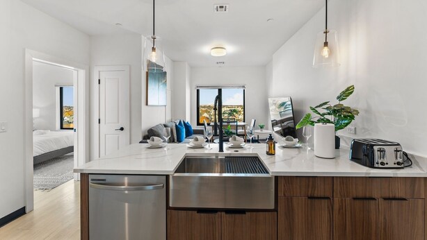 Cozinha moderna com ilha central, eletrodomésticos de aço inoxidável e iluminação pendente.