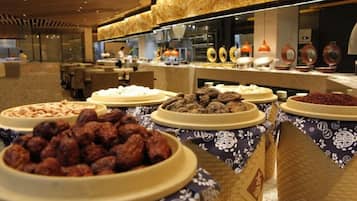 Un bufé con diversos alimentos y una zona de cocina al fondo.