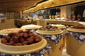 Een buffet met diverse gerechten en een keuken op de achtergrond.