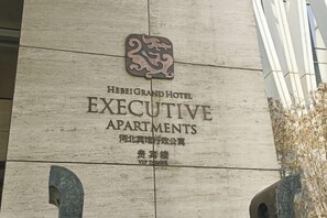 Señal para los Apartamentos Ejecutivo Hebei Grand Hotel, con logotipo y nombre tanto en inglés como en chino.