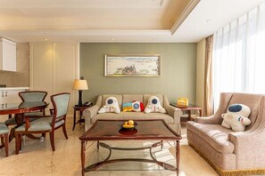 Una sala de estar con sofá, sillones, una mesa de centro y un cuadro en la pared.