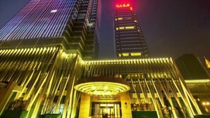 Un edificio moderno con una entrada destacada y líneas verticales iluminadas.