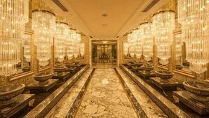 Un pasillo lujoso con candelabros, suelo de mármol y un diseño simétrico.