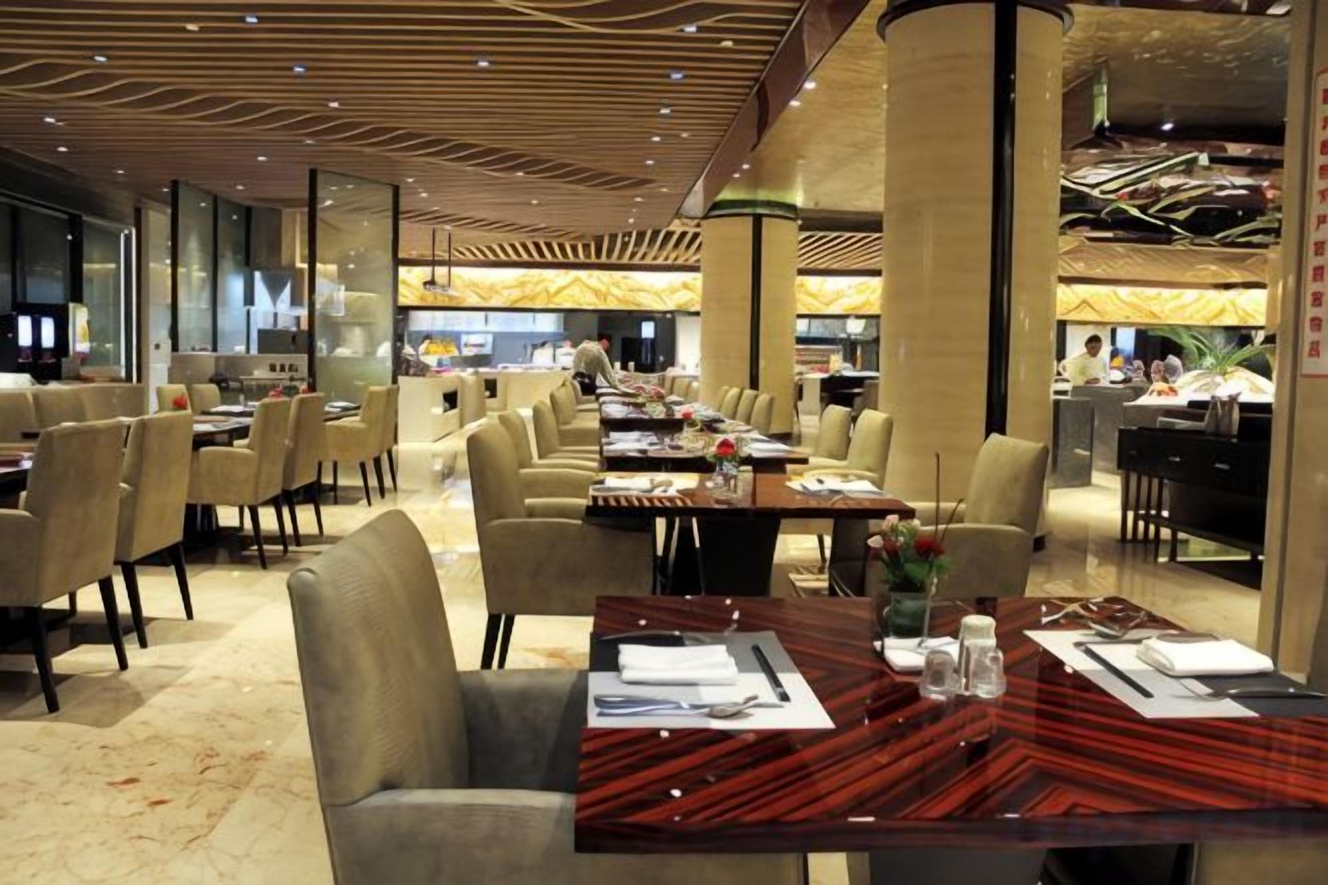 A spacious dining area with multiple tables and chairs, a long counter, and a modern ceiling design.