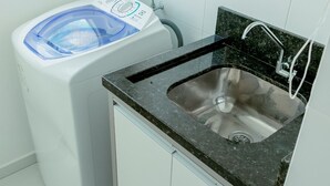 A compact kitchen with a built-in sink, a washing machine, and a small countertop. - Residencial Diva (Florianópolis)