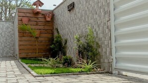A paved pathway leading to a gated entrance with a wooden fence and potted plants. - Residencial Diva (Florianópolis)