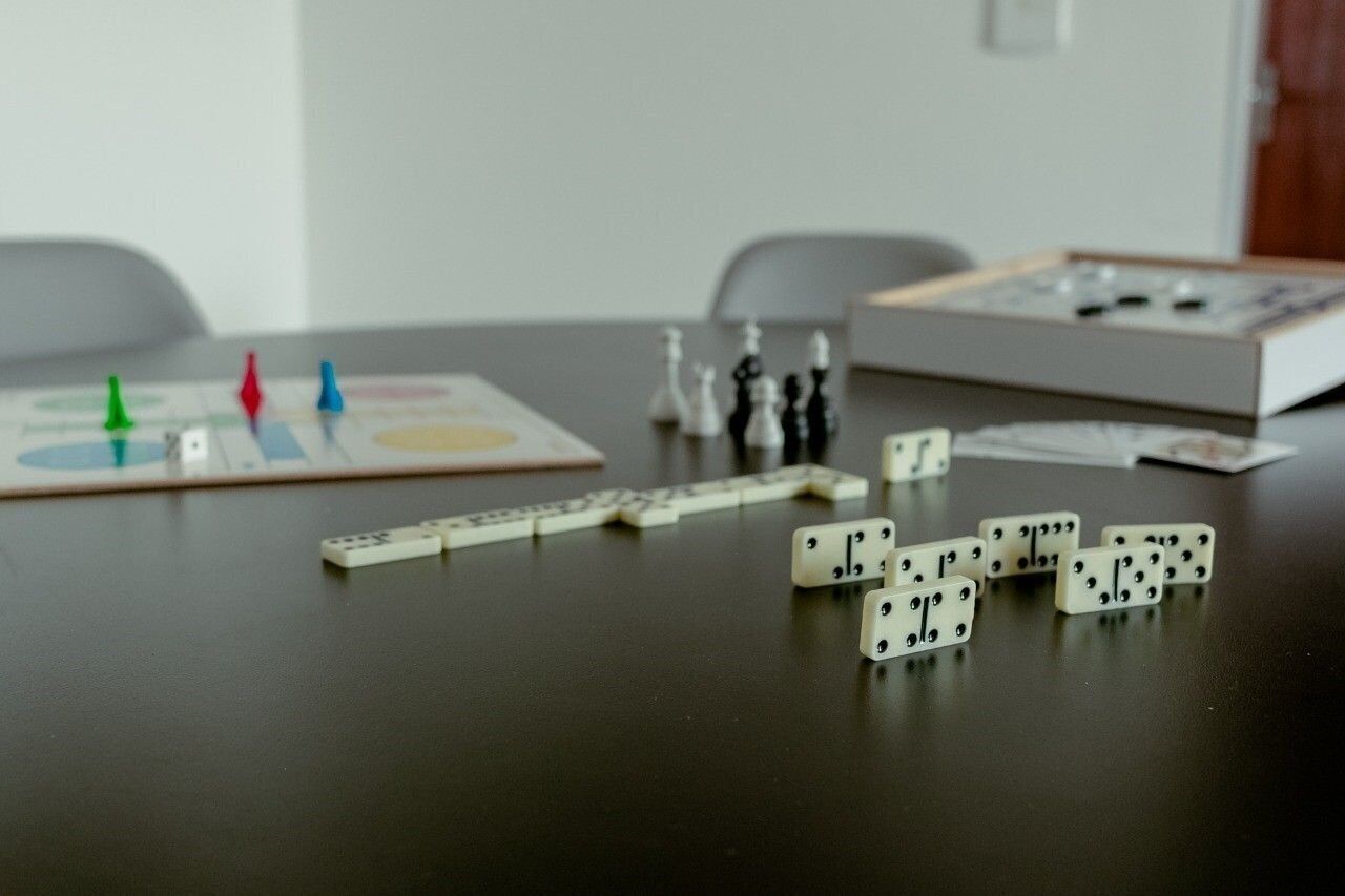 A table with dominoes, a board game, and a dice set.