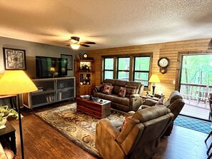 A cozy living room with a television, leather chairs, a coffee table, and a fireplace.