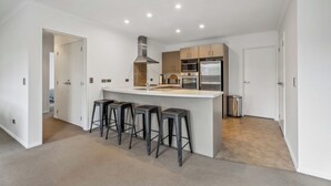 A modern kitchen with a central island, bar stools, and stainless steel appliances. - Calm at Leitrum - Cromwell Holiday Home (Cromwell)