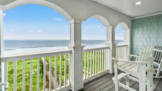 A covered porch with white railings and a view of the ocean. - Rates Reduced-Canary-Oceanfront-Shared Pool-Game Room-4000 sqft (North Myrtle Beach)