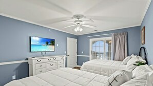 A bedroom with two beds, a TV on the wall, a ceiling fan, and a window with curtains. - Rates Reduced-Canary-Oceanfront-Shared Pool-Game Room-4000 sqft (North Myrtle Beach)