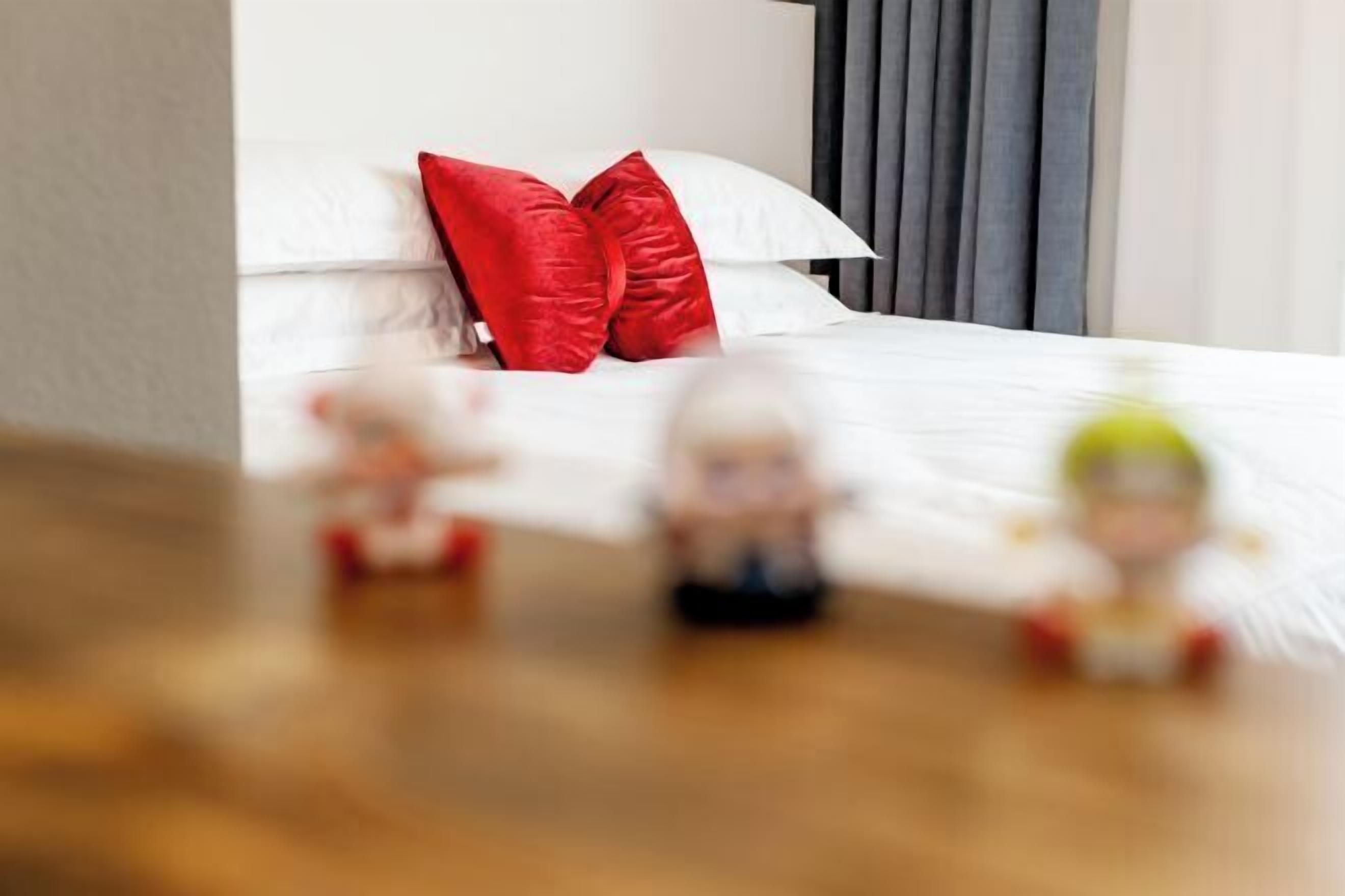 Un dormitorio con cama, almohadas y mesita de noche.