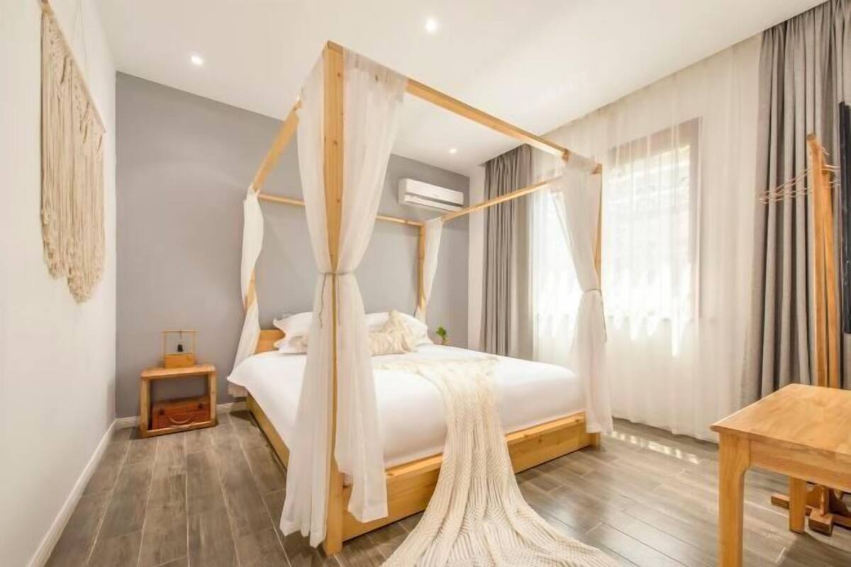 Ein Schlafzimmer mit Himmelbett, Nachttisch, kleiner Ablagefläche und Holzstuhl.