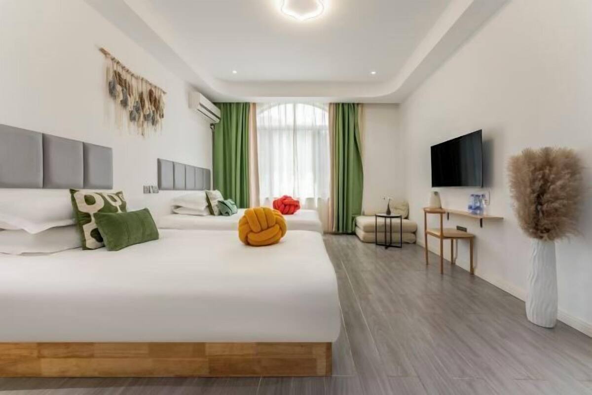 Ein modernes Hotelzimmer mit einem großen Bett, einem Fernseher, einem kleinen Tisch und einer Zierpflanze.