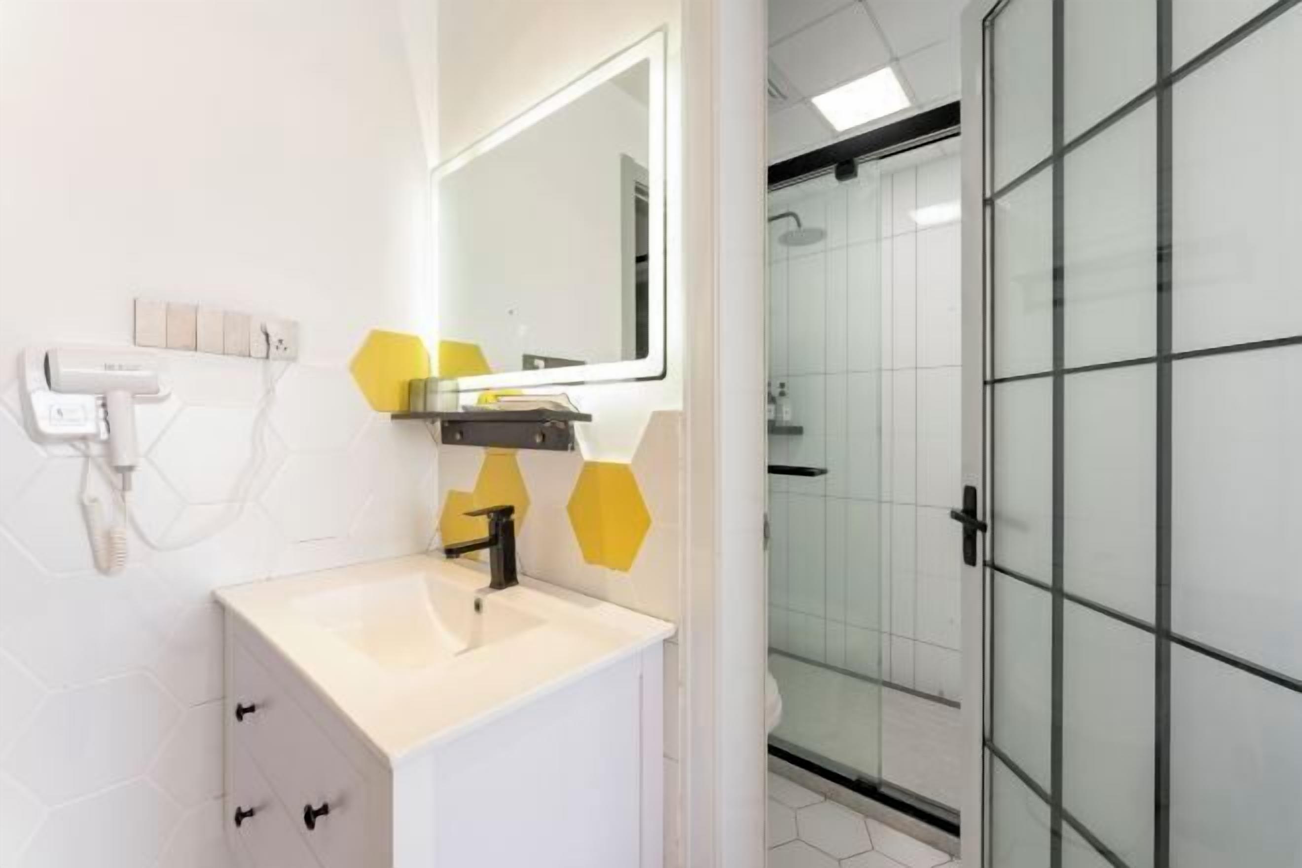 A modern bathroom with a white sink, a mirror, and a glass shower enclosure.