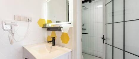 A modern bathroom with a white sink, a mirror, and a glass shower enclosure.