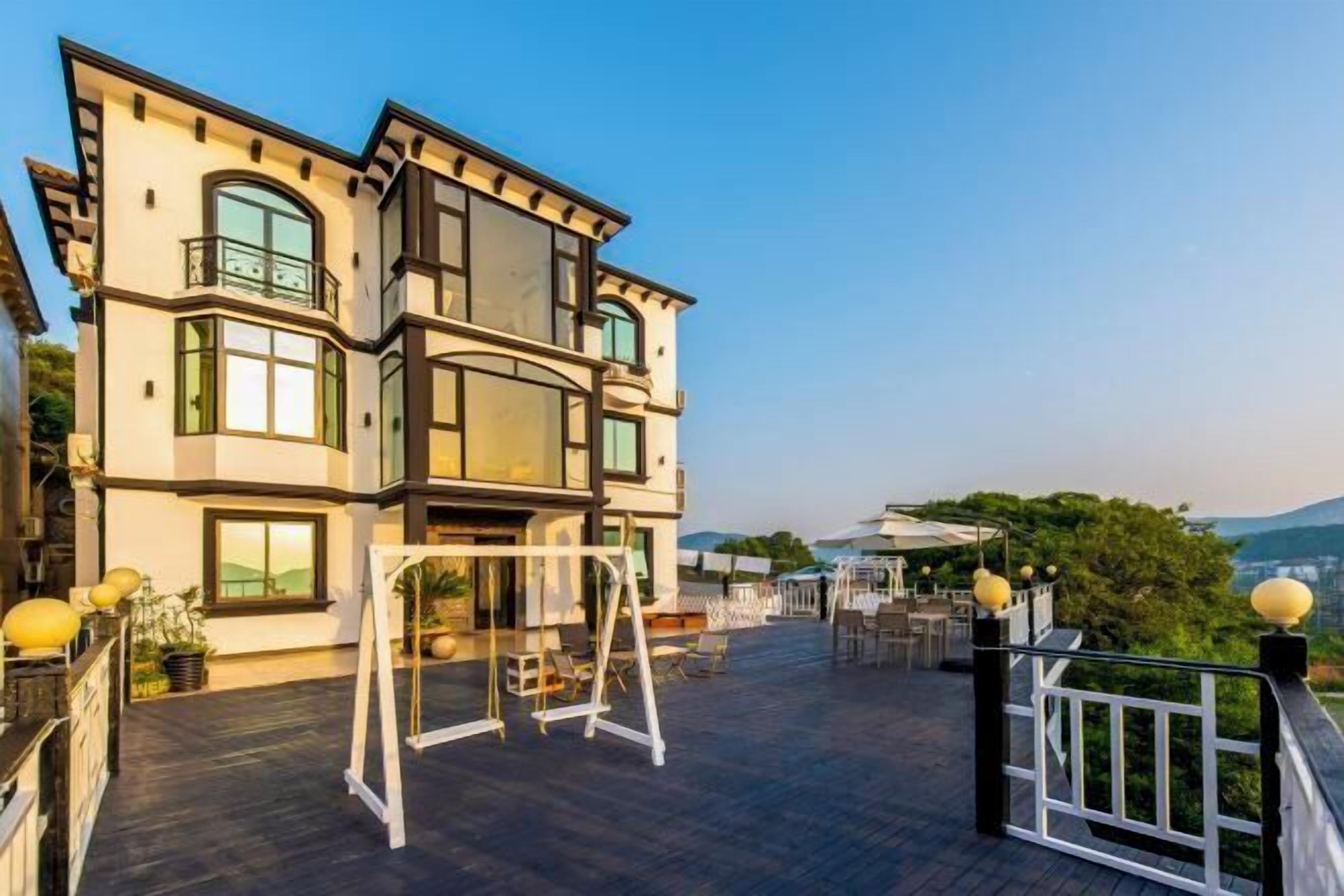 A multi-story building with a balcony area featuring outdoor furniture and a swing set.