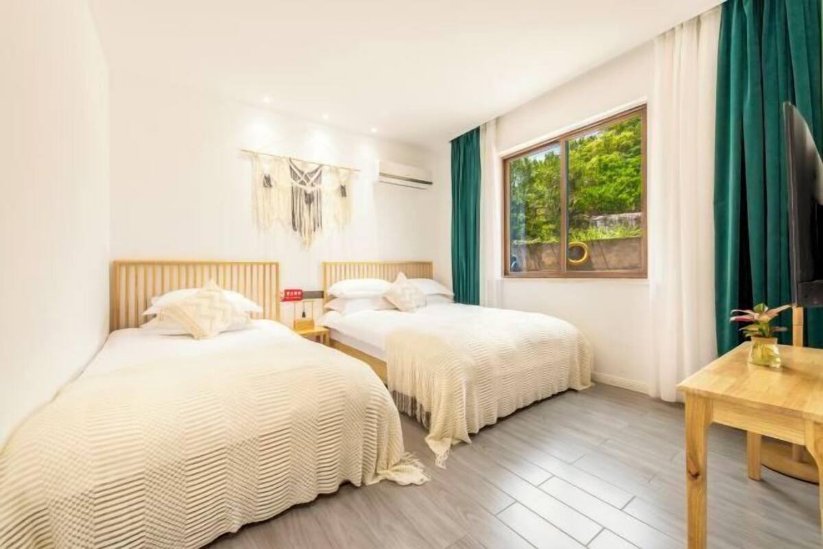 Ein Zimmer mit zwei Betten, einem Holztisch, einem Fernseher und einem Fenster mit Vorhängen.